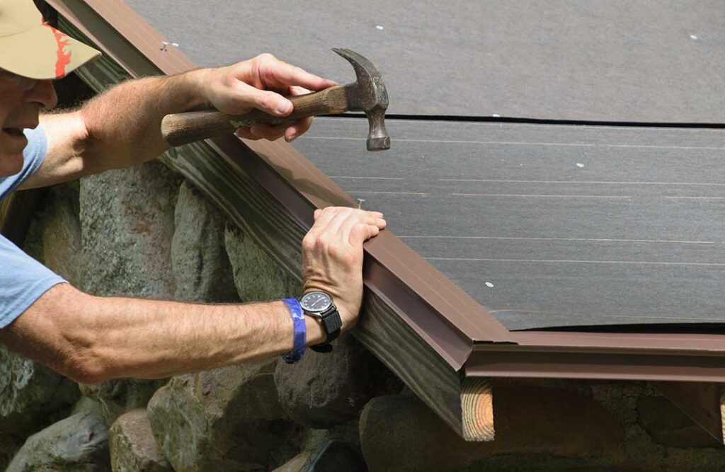 A homeowner examines a ceiling water stain while rain falls outside and roofing materials are visible above.